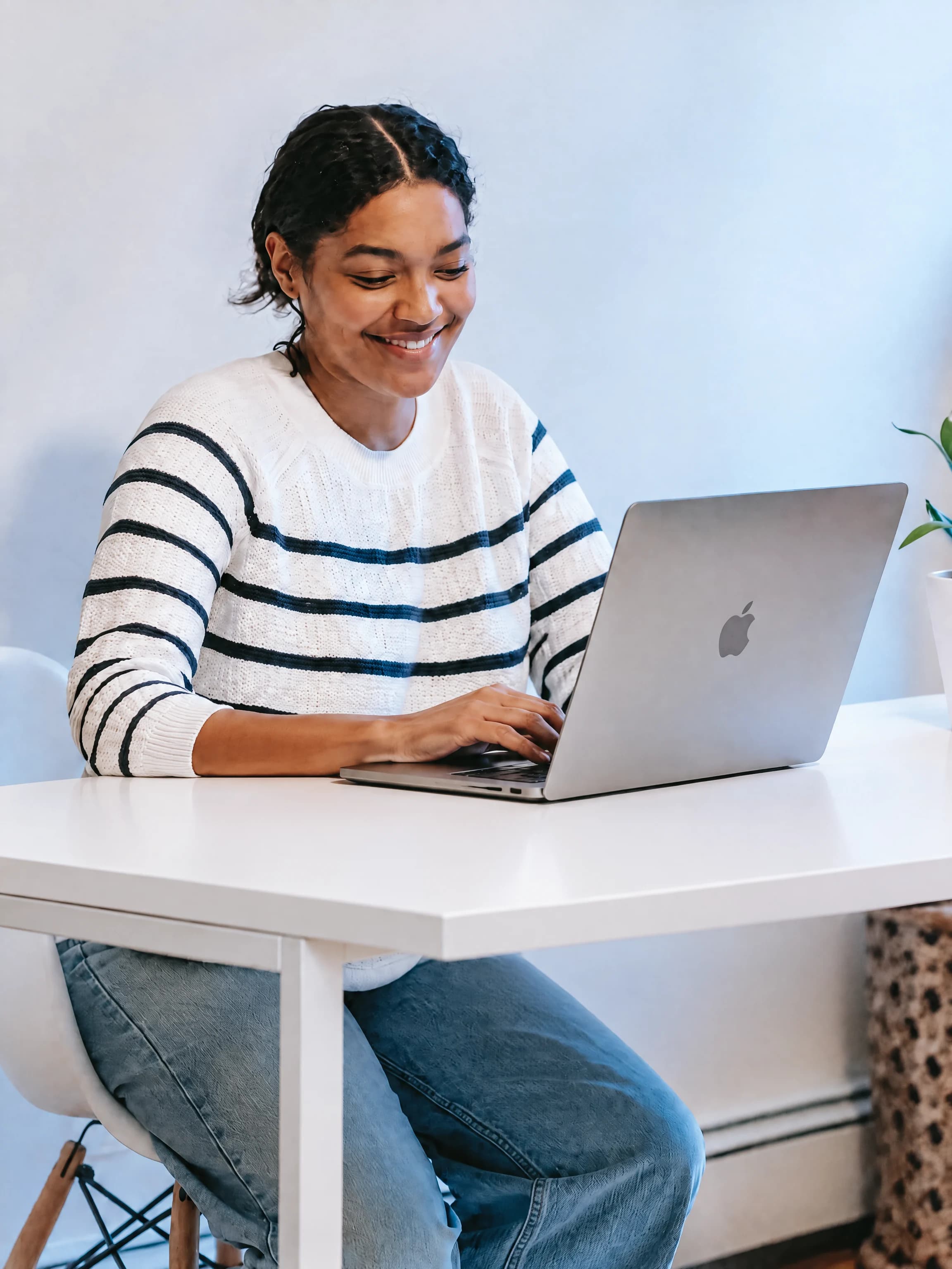 Woman working on a laptop at a clean white desk